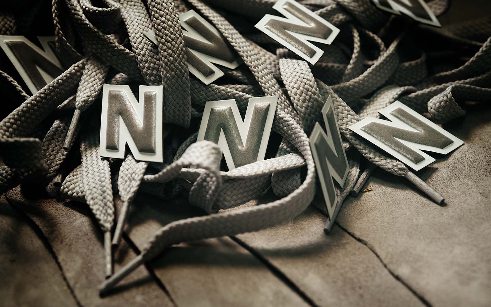 A pile of New Balance logos and shoestrings laying on a piece of suede