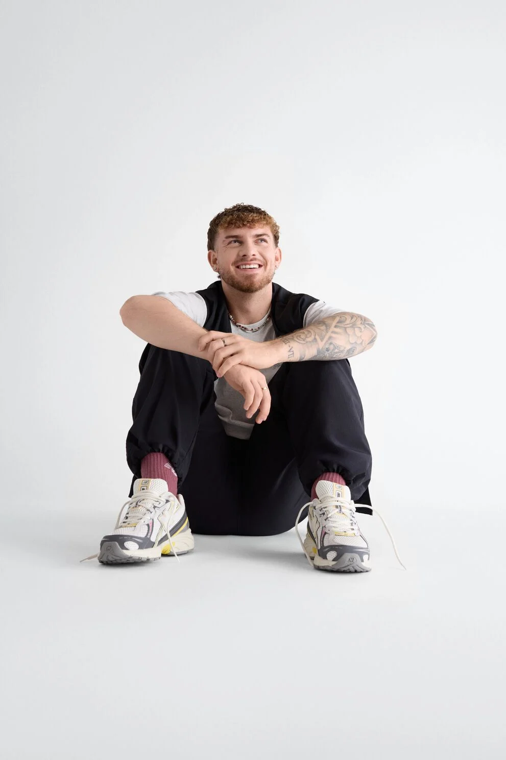 Gabby Thomas standing against a tan studio backdrop holding a pair of 471s