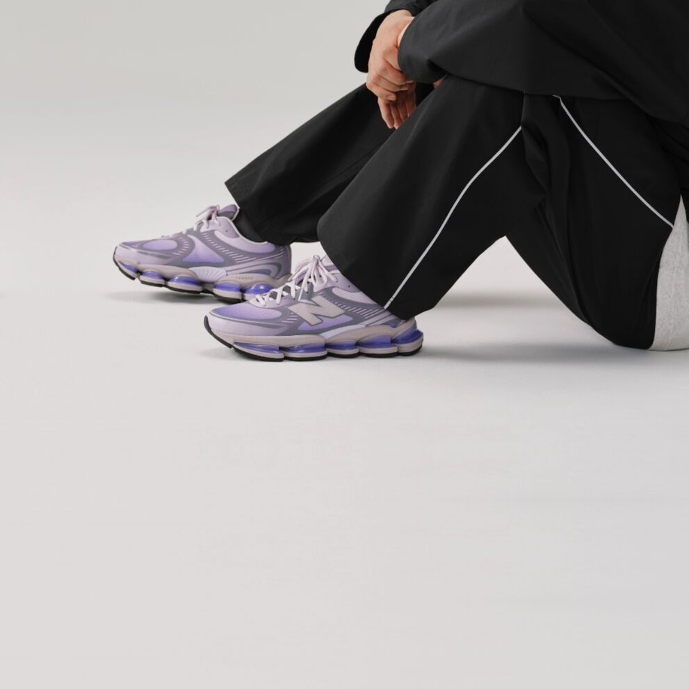 Close-up side view of a New Balance running shoe featuring a light gray mesh upper, blue &ldquo;N&rdquo; logo, white laces, and a lime-green sculpted midsole with a visible hollow cushioning design. 