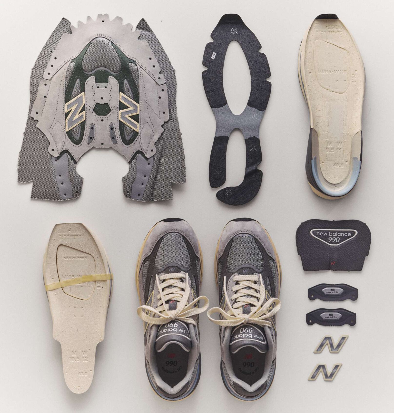 The 990v7 sneaker broken down into it's individual pieces laying on the ground.