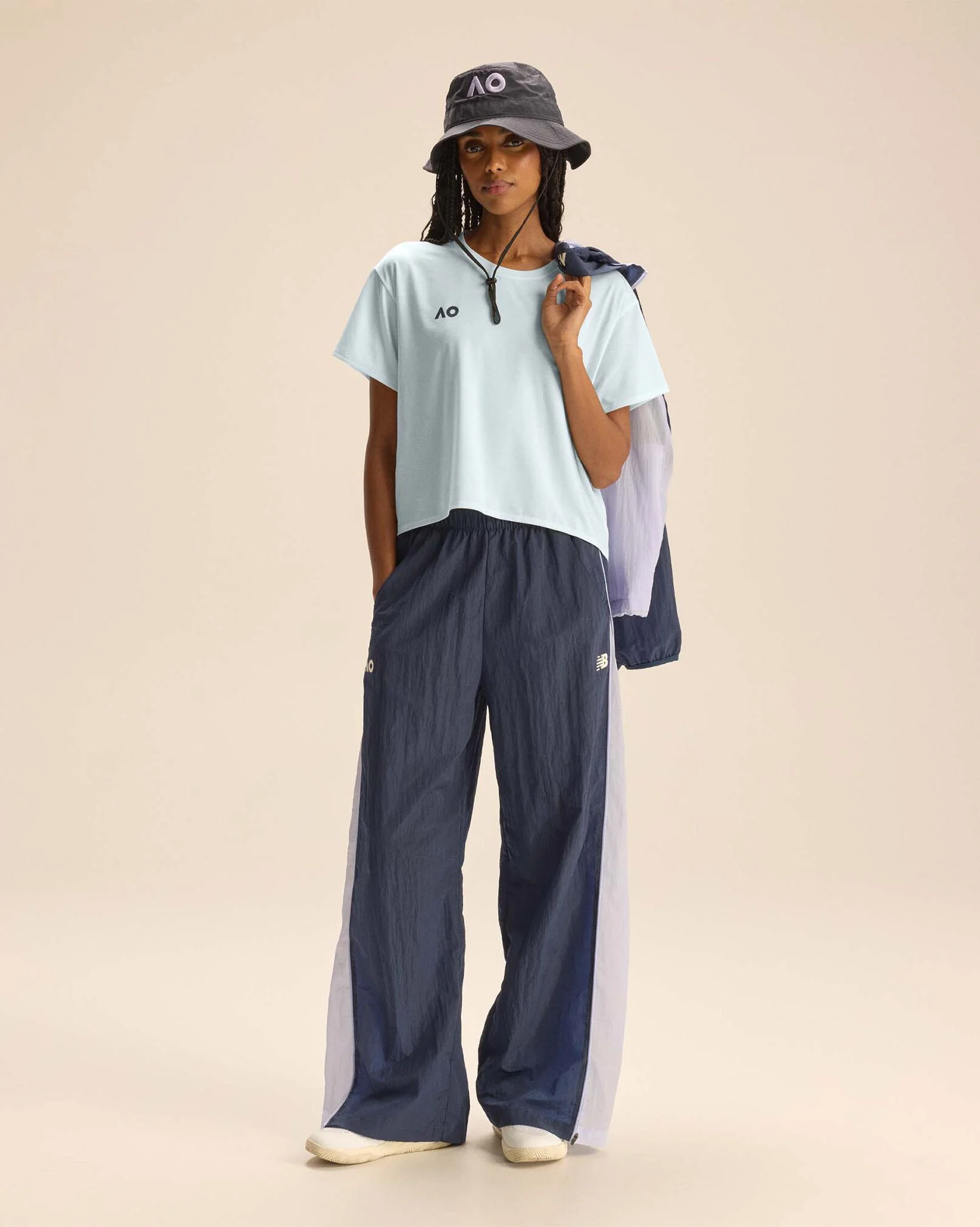 A person standing against a tan studio backdrop.