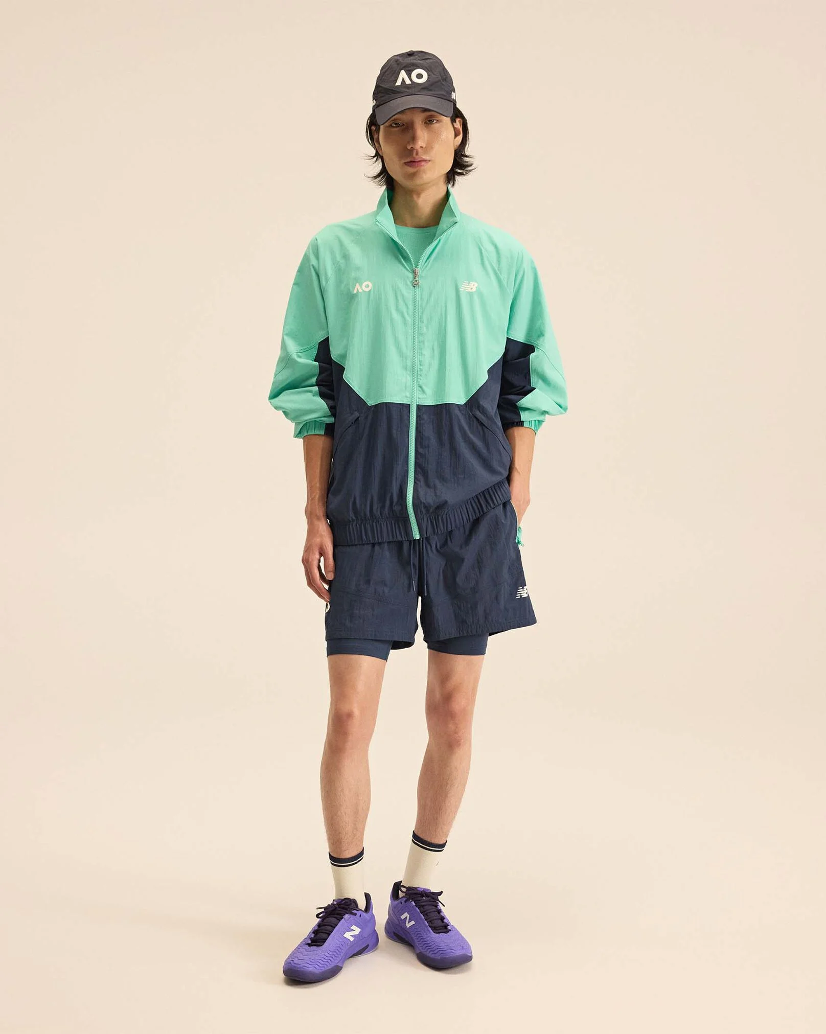 A person standing against a tan studio backdrop.