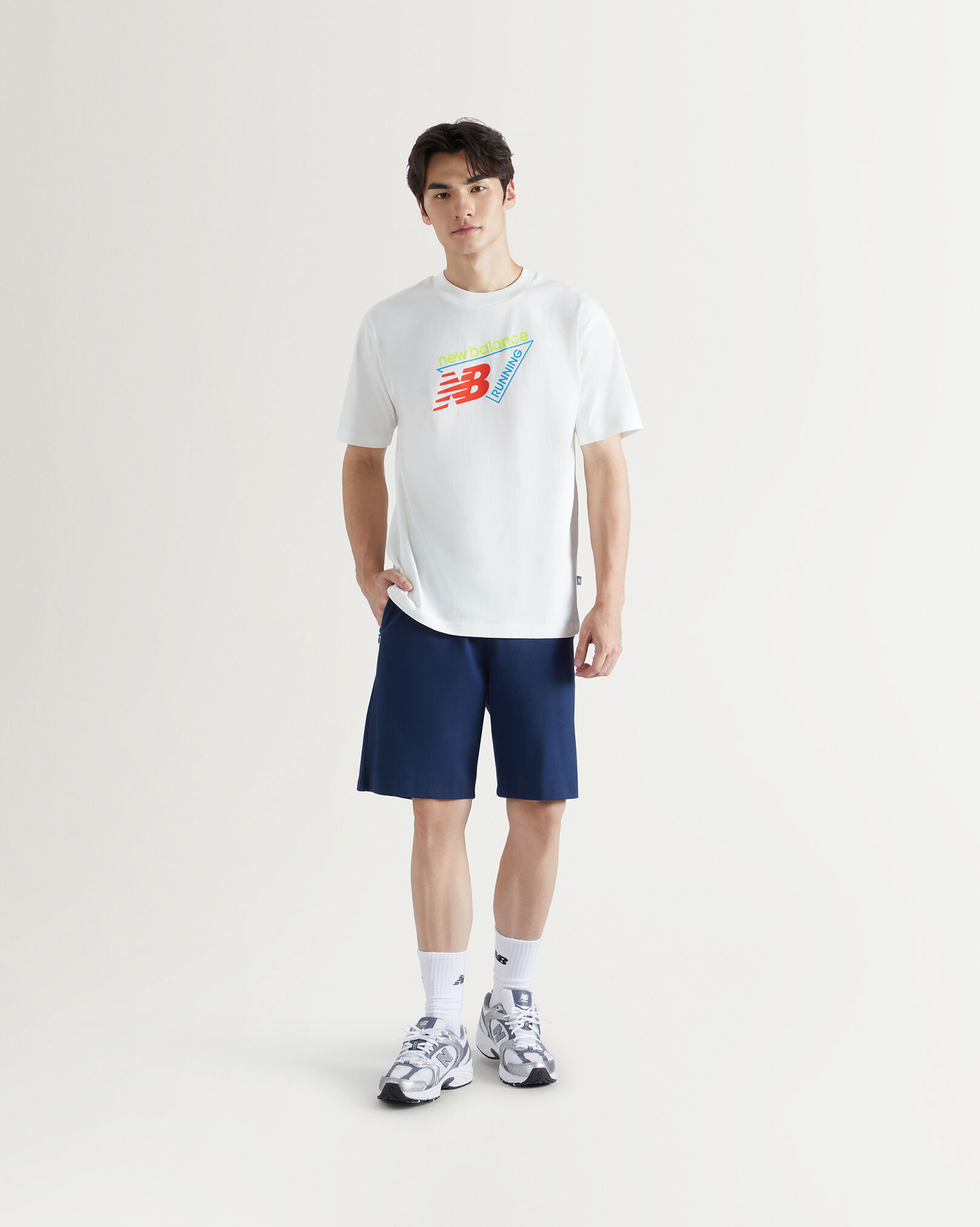 A msan standing in front a white wall.