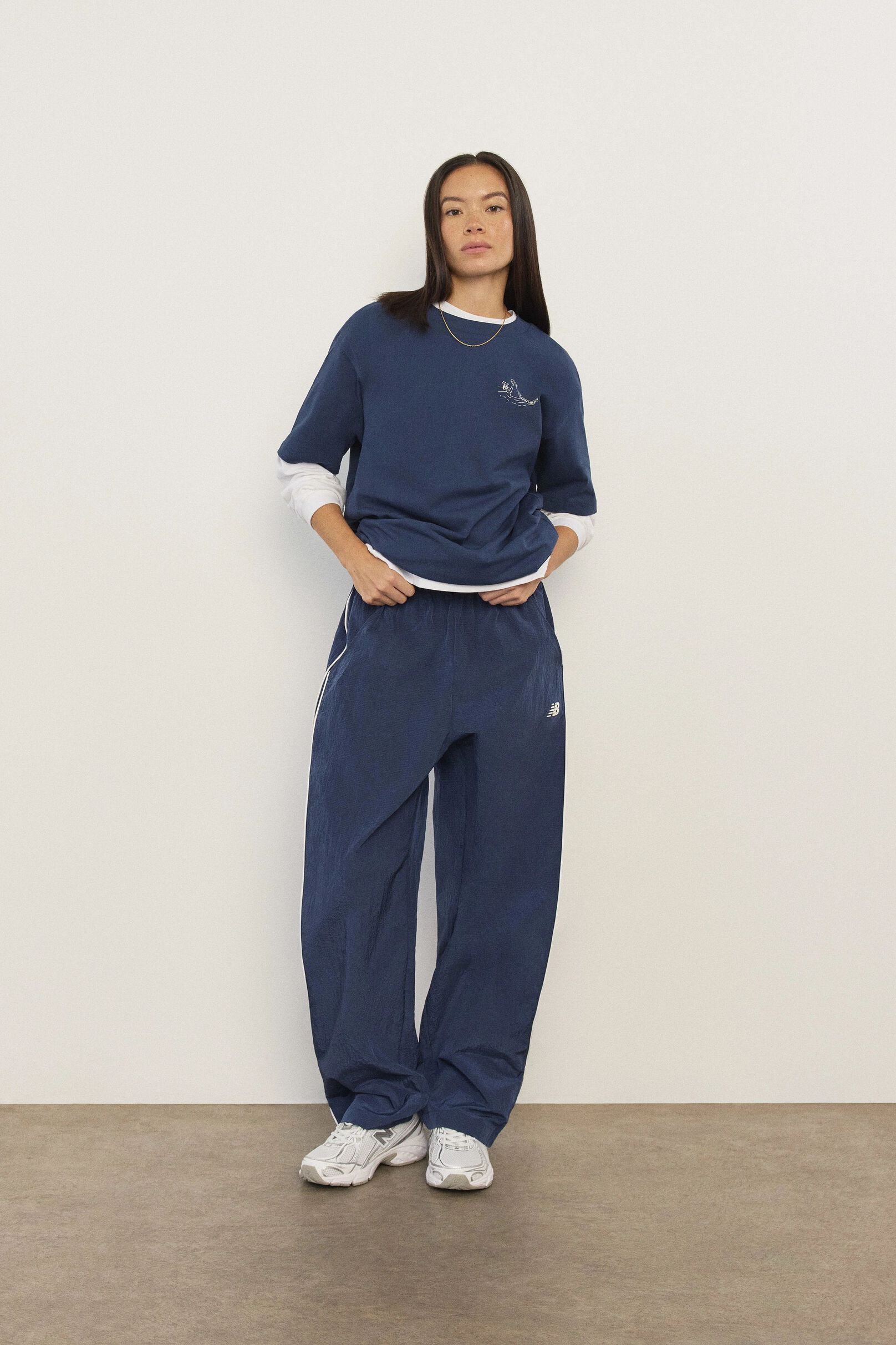 Gabby Thomas standing against a tan studio backdrop holding a pair of 471s